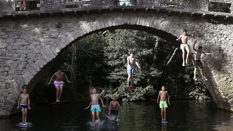 Un grupo de jóvenes saltan desde un puente al agua del río Arga en la localidad de Irotz. EFE/Jesús Diges