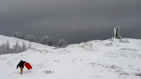 Una persona con su trineo en el Alto de Ibañeta, (Navarra), que hoy ha amanecido nevado debido a la progresiva bajada de la cota de nieve, y que ha hecho que durante la noche se movilicen máquinas quitanieves de forma preventiva. EFE/VILLAR LÓPEZ