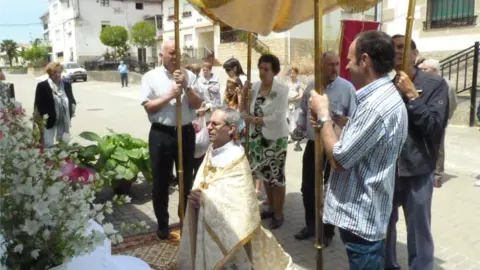 La procesión se detiene junto a un altar en la calle.
