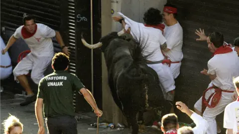 Un toro de la ganadería gaditana de Cebada Gago cren una situación de peligro ante un grupos de mozos a la entrada de la calle Mercaderes de Pamplona . EFEVillar López