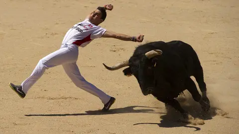 Un recortador hace un quiebro a un toro durante el concurso de recortadores celebrado esta mañana en la Plaza de Toros de Pamplona dentro de los actos populares de las fiestas de San Fermín. EFE/Villar López