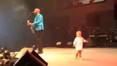 Este bebé sube al escenario a acompañar a su padre y se hace con el público. 
