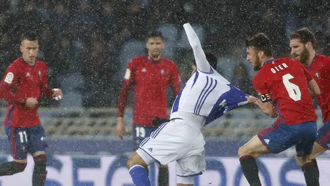 El delantero mexicano de la Real Sociedad Carlos Vela (c) sufre una falta de Oier Sanjurjo, defensa de Osasuna, durante el encuentro de la jornada 21 de Liga en Primera División que se juega esta tarde en el estadio de Anoeta, en San Sebastián. EFE/Javier Etxezarreta.