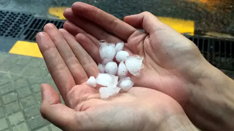 Una persona recoge las pelotas de granizo que han caído sobre la Comarca de Pamplona.