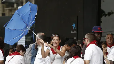 Varias personas intentan protegerse de la lluvia acompañada de fuerte viento que ha caído este mediodía en Pamplona, en el tercer día de fiestas de San Fermin 2017. EFE/Jesús Diges