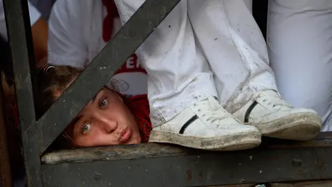 Varias chicas descansan y tratan de dormir en el vallado antes del encierro de Sanfermines, para el que han conseguido un sitio para verlo a pie de calle. REUTERS