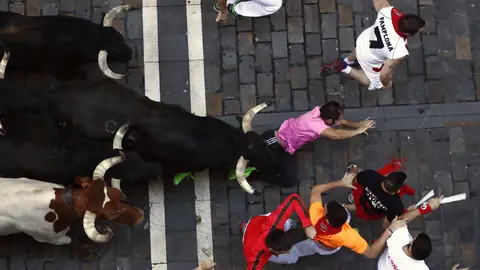 GRA019. PAMPLONA, 12/07/2017.- Varios mozos corren ante un la manada de toros de la ganadería madrileña de Victoriano del Río, a su llegada a la calle Estafeta durante el sexto encierro de los Sanfermines 2017. EFE/Jesús Diges