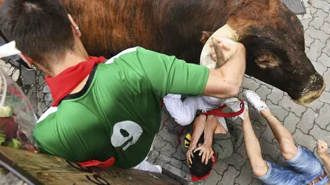 GRA056. PAMPLONA, 14/07/2017.- Un astado de la ganadería de Miura, de Lora del Río (Sevilla), protagoniza uno de los momentos más peligrosos de la carrera en el tramo de Telefónica, durante el último encierro de los Sanfermines 2017. La bella estampa de los toros de Miura ha cerrado los encierros de este año con la carrera más corta de las fiestas, de dos minutos y diez segundos, que se ha saldado con al menos cinco heridos trasladados al Complejo Hospitalario de Navarra, ninguno de ellos por asta, según fuentes sanitarias. EFE/Daniel Fernández