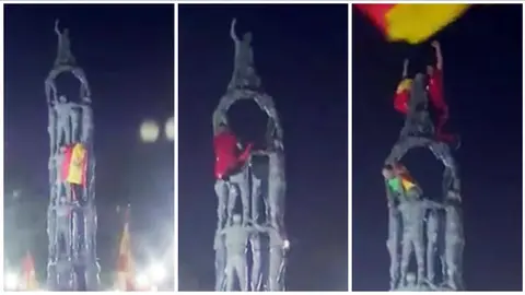 Un joven escala el monumento de los Castellers en Tarragona para colocar una bandera de España.