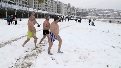 GRAF1482. SAN SEBASTIÁN, 28/02/2018.- Un grupo de bañistas se dirigen al agua en la bahía de la Concha de San Sebastián. Cuarenta provincias de catorce comunidades continúan hoy en alerta por el temporal que deja bajas temperaturas, riesgo de aludes, intenso oleaje, rachas intensas de viento y fuertes nevadas de hasta 35 centímetros de espesor en zonas de montaña, informa la Agencia de Meteorología (Aemet) en su web. Aragón tiene activada la alerta naranja (riesgo importante) en Huesca y Zaragoza por nevadas que dejarán acumulaciones entre los 5 y 35 centímetros en áreas de las Cinco Villas, Ribera del Ebro y Pirineo oscense, y aviso amarillo en Huesca por viento, aludes y temperaturas mínimas, y en Teruel por nieve. Las comunidades de Navarra, La Rioja y País Vasco continúan en alerta naranja por nevadas, viento o aludes mientras que en Galicia hay aviso naranja por nieve en Lugo y Orense y por fuerte oleaje que alcanzará entre los 5 y 6 metros en el litoral de A Coruña. EFE/ Juan Herrero
