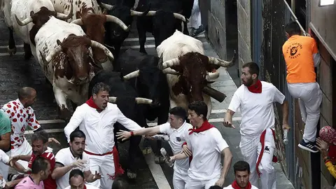 Los toros de la ganadería madrileña de Victoriano del Rio Cortés enfilan la calle Estafeta junto a mansos y mozos durante el sexto encierro de los Sanfermines 2018. EFE/Jesús Diges