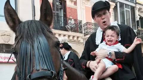 Un niño llora subido en brazos de uno de los caballeros en plaza durante el desfile de las mulillas en los Sanfermines de 2018