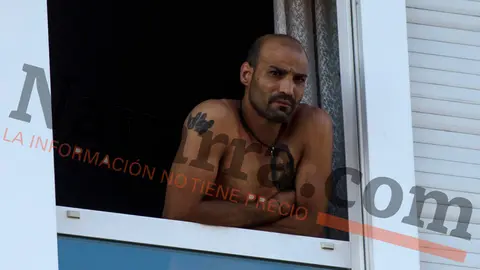 El hombre atrincherado en su vivienda del barrio de San Jorge en Pamplona, Moisés Fernández, se asoma a la ventana antes de entregarse a la policía. MIGUEL OSÉS