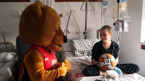 Alexandra Oliver con la mascota del equipo Ronky en la visita del Basket Navarra a los niños ingresados en el Complejo Hospitalario de Navarra. GOBIERNO DE NAVARRA