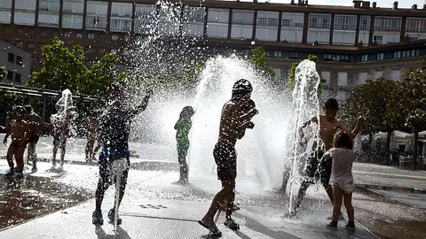 Unos niños juegan en la 'fuente de chorros' de la Plaza de Yamaguchi durante la primera ola de calor del verano en Pamplona. IÑIGO ALZUGARAY