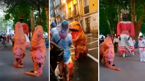 Dos personas disfrazadas de dinosaurios acompañan a la giganta Braulia en un recorrido antes de San Fermín y sorprenden a unas personas ya en plenas fiestas CEDIDAS
