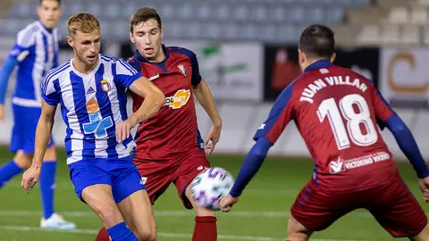 El jugador del Lorca Deportiva George Higgins (i) juega un balón entre Jon Moncayola (c) y Juan Villar, ambos de Osasuna, durante el partido de la Copa del Rey de fútbol disputado esta noche en el estadio Artés Carrasco de Lorca. EFE/Marcial Guillén.