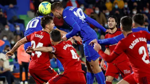 El delantero del Getafe, Dario Poveda (c), marca de cabeza el primer gol de su equipo ante el Osasuna durante el encuentro correspondiente a la jornada decimoctava de primera división que disputan hoy domingo frente al Getafe en el coliseum Alfonso Pérez de la localidad madrileña. EFE / Mariscal.
