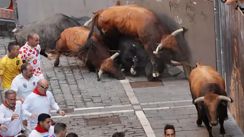 Los toros de la ganadería gaditana de Cebada Gago caen a su llegada a la curva de Mercaderes antes de enfilar la Estafeta durante el quinto encierro de los Sanfermines, este lunes en Pamplona. EFE Villar López