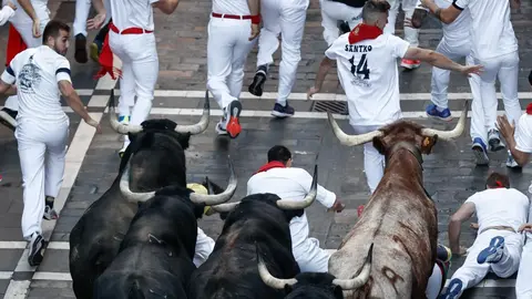Los mozos corren por la calle de Mercaderes durante el séptimo encierro de los Sanfermines ante los toros de la ganadería de Victoriano del Río Cortés. este miércoles en Pamplona. EFE Jesus Diges