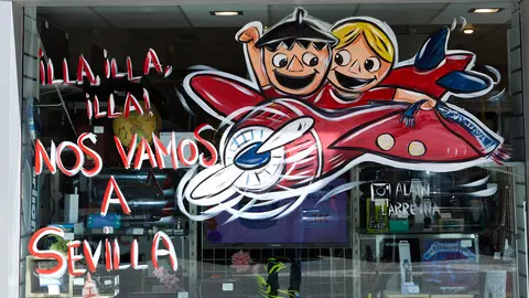 El pintor Alain Larreina y la Asociación Ensanche Área Comercial han creado la iniciativa de los escaparates rojillos para que los locales de la zona luzcan dibujos relacionados con la final de Copa del Rey de Osasuna. IÑIGO ALZUGARAY