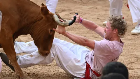 Uno de los mozos es corneado por una de las vaquillas en la plaza de toros de Pamplona, al término del primer encierro de los sanfermines 2023. EFE/Eloy Alonso