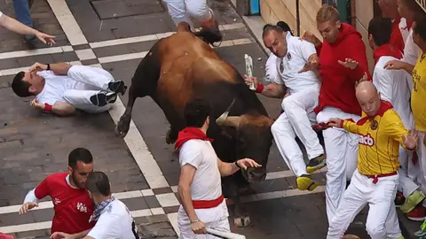 Un mozo es volteado por un toro de la ganadería de Fuente Ymbro al inicio de la calle de la Estafeta durante el cuarto encierro de los sanfermines 2023, este lunes. EFE -J.P. Urdiroz