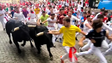 Un mozo corre delante de un Victoriano del R&iacute;o en la bajada al callej&oacute;n en el tercer encierro de San Ferm&iacute;n. NAVARRA.COM
