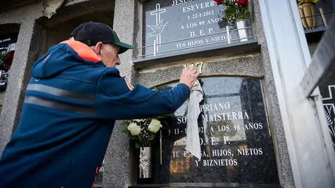 Varias personas llevan flores a sus sere queridos durante la celebración de Todos los Santos en el cementerio de Pamplona. PABLO LASAOSA