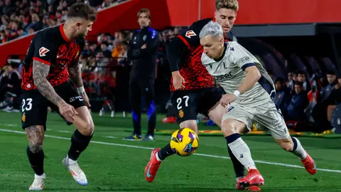 El centrocampista del Mallorca Robert Navarro (c) pelea un balón con el delantero de Osasuna Bryan Zaragoza (d) en el partido de LaLiga entre el Mallorca y el Osasuna, este lunes en el estadio de Son Moix, en Palma. EFE/CATI CLADERA