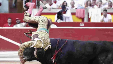El torero Fernando Adrián sufre un revolcón durante la lidia a su segundo toro de la tarde en la novena de abono de la Feria de Toro de los Sanfermines 2025 con toros de la ganadería gaditana La Palmosilla y en la que comparte cartel con los diestros Jiménez Fortes y Ginés Marín. EFE/Jesús Diges
