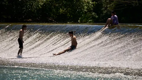 Decenas de personas aprovechan las altas temperaturas para refrescarse y disfrutar del r&iacute;o Arga a su paso por Pamplona. PABLO LASAOSA