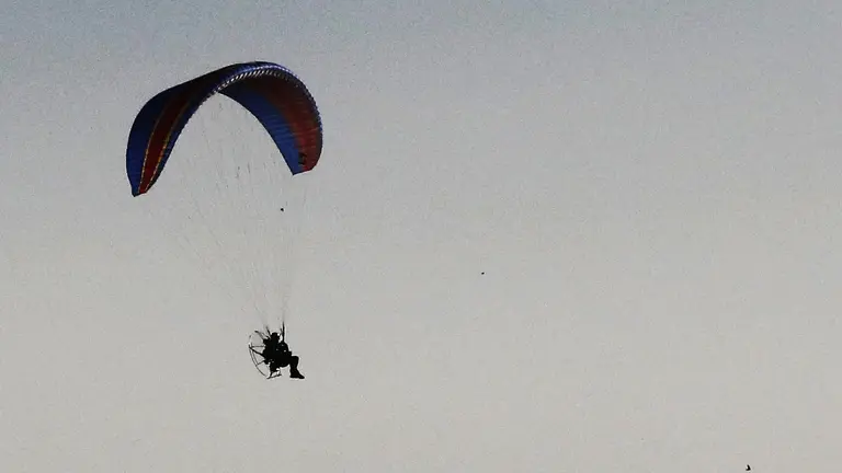 Un parapente con motor sobrevuela por un parque e&oacute;lico en la localidad de Falces, en una jornada en la que el buen tiempo,  las altas temperaturas y la ausencia de viento permiten disfrutar desde el aire de unas privilegiadas panor&aacute;micas. EFE/Jes&uacute;s Diges