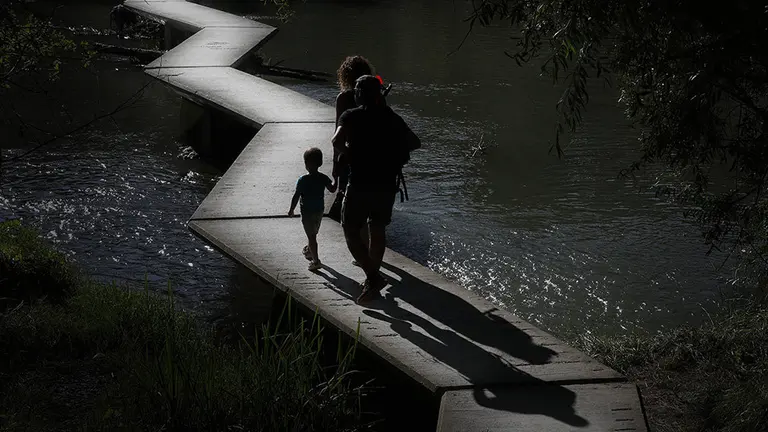 Una familia atraviesa la pasarela del r&iacute;o Arga a su paso por Pamplona en un d&iacute;a marcado por el tiempo soleado. EFE/Villar L&oacute;pez