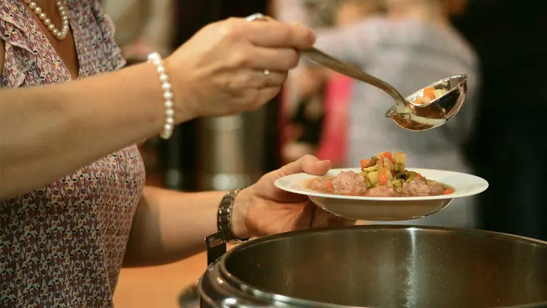 Una voluntaria llena un plato de comida en un comedor social. ARCHIVO