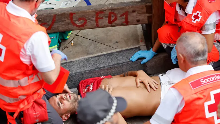 Los sanitarios atienden a un mozo herido por los toros de la ganadería Jandilla durante el quinto encierro de los Sanfermines este viernes en Pamplona. EFE Villar López