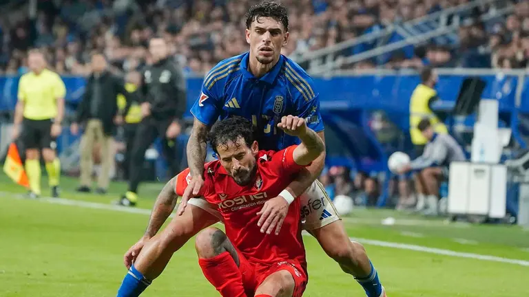 El defensa del Oviedo Javier López (detrás) pelea un balón con el centrocampista del Osasuna Rubén García durante el partido de la jornada 11 de LaLiga EA Sports que disputan el Real Oviedo y el Osasuna este lunes, en el estadio Carlos Tartiere. EFE/ Paco Paredes