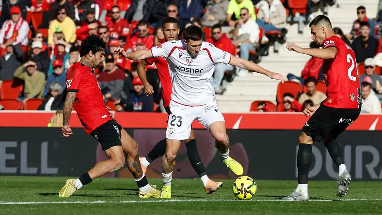 El defensa del Osasuna Abel Bretones (c) disputa la posesión del balón con jugadores del RCD Mallorca durante el partido liguero entre el RCD Mallorca y el Osasuna celebrado en el estadio Son Moix, Palma de Mallorca, este sábado. EFE/ Cati Cladera