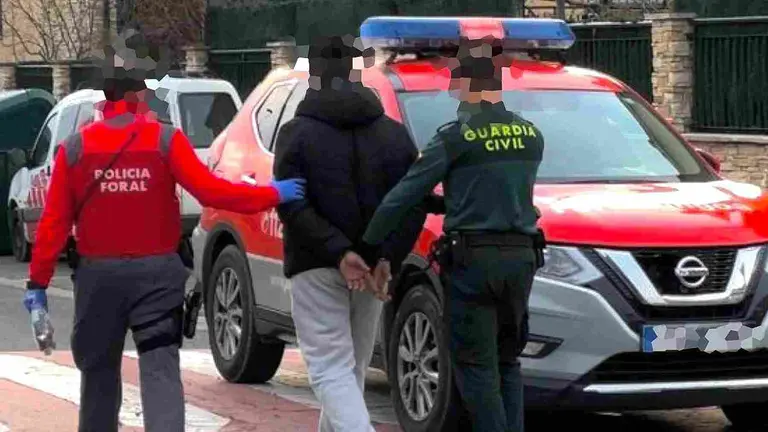 Un agente de la Policía Foral y un agente de la Guardia Civil conducen al detenido a comisaría. POLICÍA FORAL