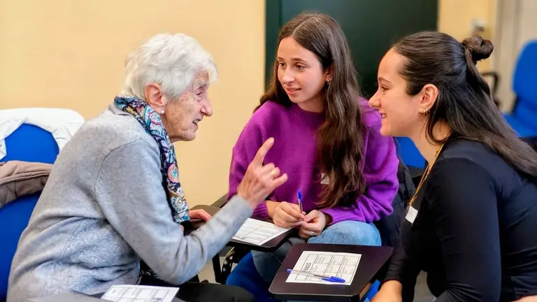 Una de las participantes en el encuentro charla con dos estudiantes. UPNA