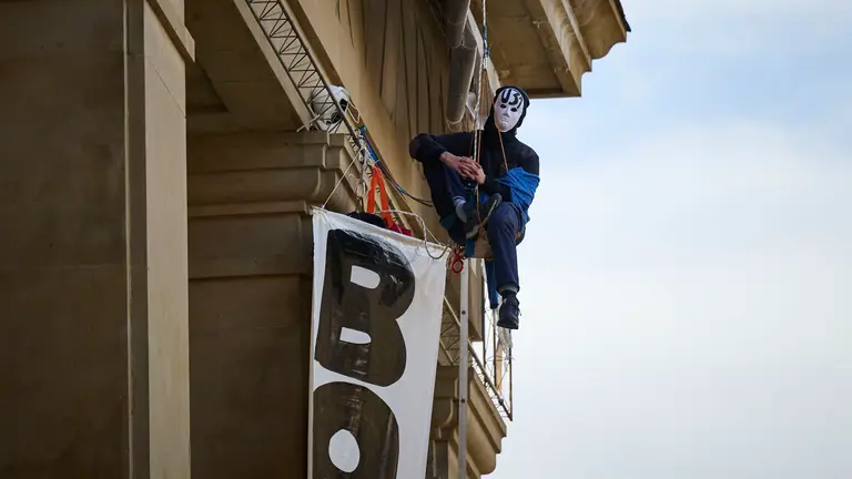 Dos personas se cuelgan del monumento a Los Ca&iacute;dos de Pamplona en la Plaza de la Libertad. PABLO LASAOSA