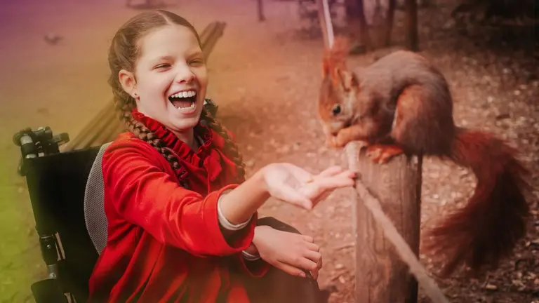 Una ni&ntilde;a en silla de ruedas juega con una ardilla. CINFA