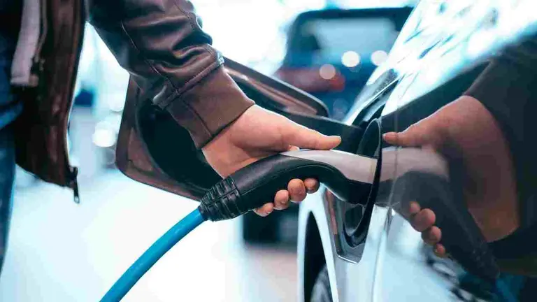 Un hombre conecta el cargador de un coche el&eacute;ctrico. ARCHIVO