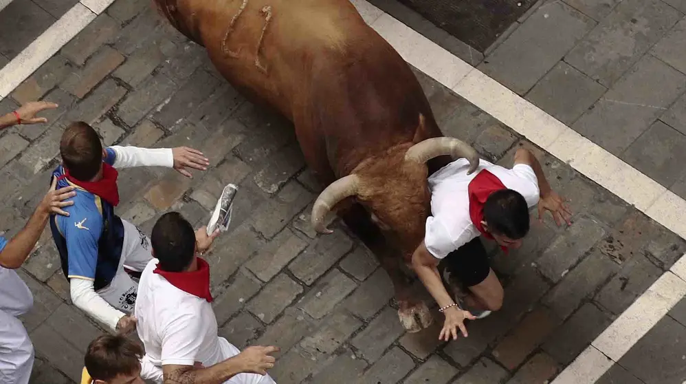 GRA020. PAMPLONA, 13/07/2017.- Un toro de la ganadería gaditada de Núñez del Cuvillo arrolla a un mozo en el tramo inicial de la calle Estafeta, durante el séptimo encierro de los San Fermines 2017, en el que las reses han protagonizado una rápida carrera de dos minutos y diez segundos hasta la arena de la plaza, y en la que, hasta el momento, se han contabilizado dos heridos por asta y un contusionado. EFE/Juan Pedro Urdíroz