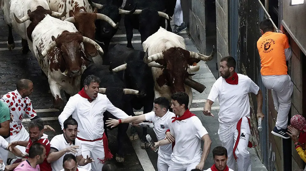 Los toros de la ganadería madrileña de Victoriano del Rio Cortés enfilan la calle Estafeta junto a mansos y mozos durante el sexto encierro de los Sanfermines 2018. EFE/Jesús Diges
