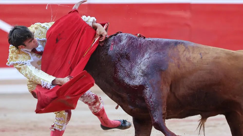 El diestro Adrián Torres sufre un percance al entrar a matar a su segundo toro en suerte esta tarde en la Plaza de Toros de Pamplona dentro de la Feria del Toro de los Sanfermines 2023, donde ha compartido cartel con Román Collado e Isaac Fonseca con toros de la ganadería gaditana de José Cebada Gago. EFE - Villar López