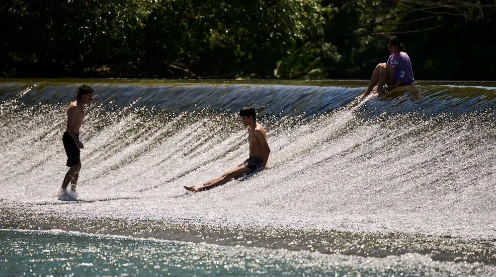 Decenas de personas aprovechan las altas temperaturas para refrescarse y disfrutar del r&iacute;o Arga a su paso por Pamplona. PABLO LASAOSA