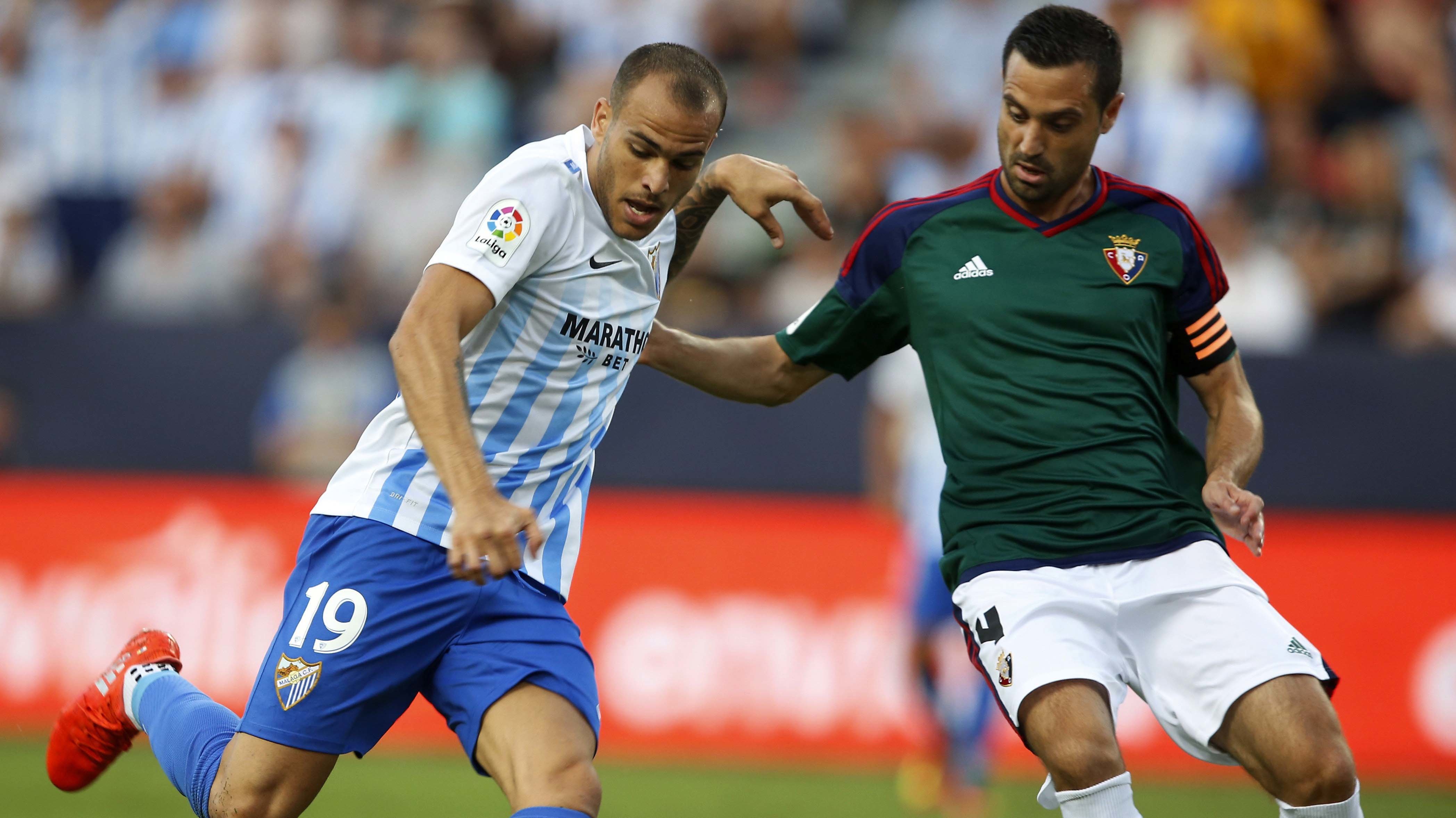 El defensa del Club Atlético Osasuna M. Flaño (d) lucha el balón con el delantero del Málaga CF, Sandro (i), durante el partido de la primera jornada de Liga en Primera División que se disputa esta noche en el estadio de La Rosaleda, en Málaga. EFE/Carlos Díaz.