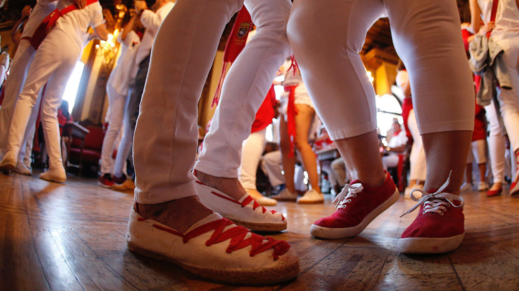 GRAFCAV6324. PAMPLONA (NAVARRA), 10/07/2019.- Todos los días de San Fermín a las 9 horas se celebra el Baile de la alpargata en el Nuevo Casino situado en la Plaza del Castillo de Pamplona. Es habitual acudir después del encierro. Los asistentes pueden sentarse en las mesas a desayunar chocolate con churros o salir a la pista de baile donde una animadora dirige las coreografías de canciones populares. El baile comenzó con la costumbre de los socios de Casino de desayunar tras el encierro. Con los años se fue amenizando con música y se convirtió que el baile que todos conocen en la actualidad. En sus inicios, se exigía cierto decoro en el vestir, pero muchos socios llegaban después de correr el encierro calzados con alpargatas (cómodas para correr). Parece que el nombre del Baile de la alpargata proviene de esta tradición de saltarse las normas tras el encierro. EFE/Javier Lizón