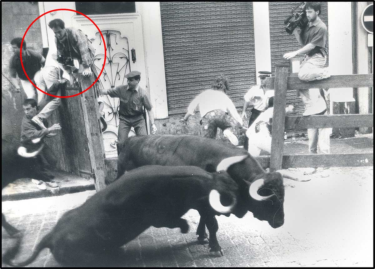 En el circulo un joven Javier Sesma, con dos cámaras, encaramado a duras penas en la puerta tras el embiste de un toro contra el poste en la curva de Mercaderes.